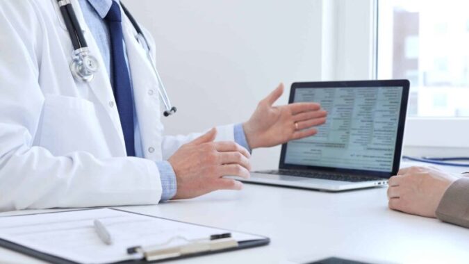 Close-up of a doctor reviewing digital test results with patient, discussing health findings on laptop screen during clinical consultation. Medicine and health care concept Common reasons for diagnostic delays in gastroparesis